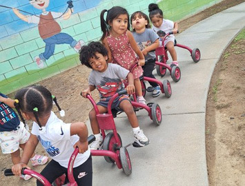 Children riding tricycles together on Kingston’s outdoor path