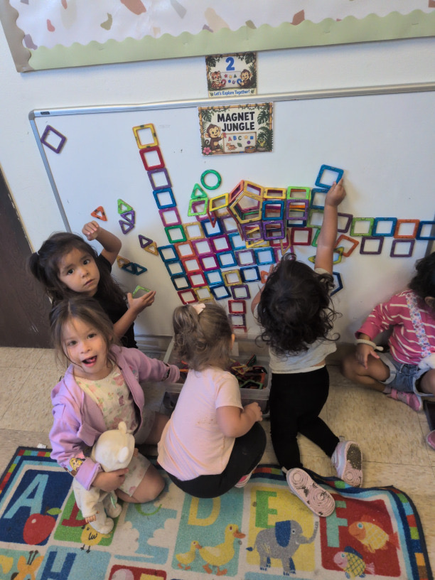 Children playing together at a wall of colorful magnetic shapes