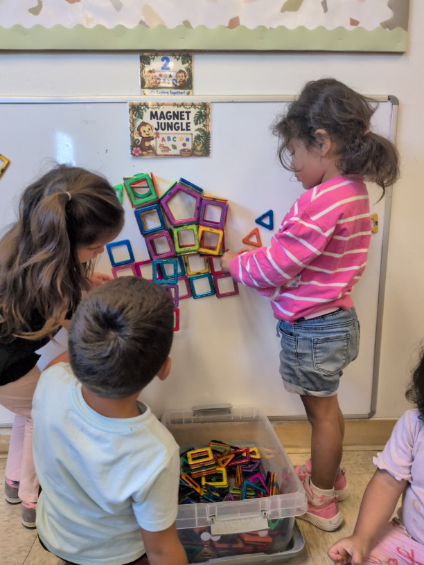 Children arranging colorful magnetic shapes on a classroom board