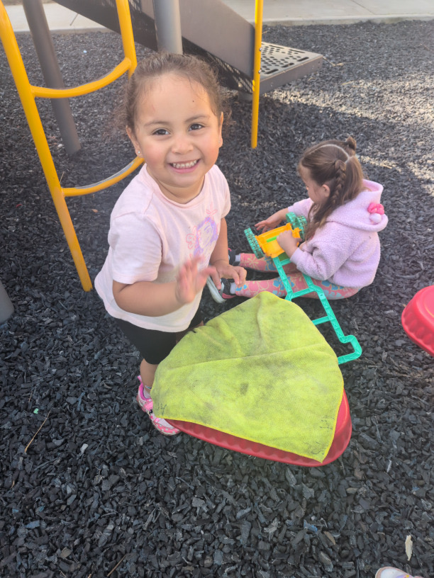 A smiling child holding a green basket outside