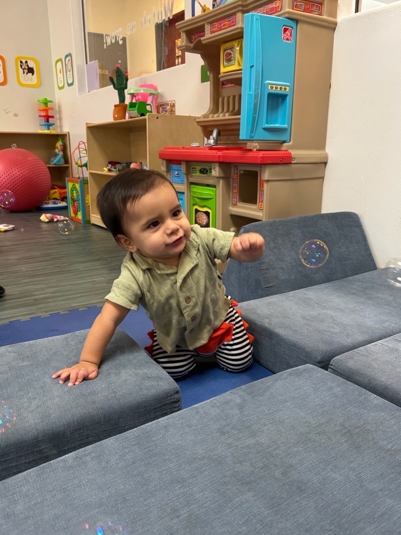 A child reaching for bubbles outside