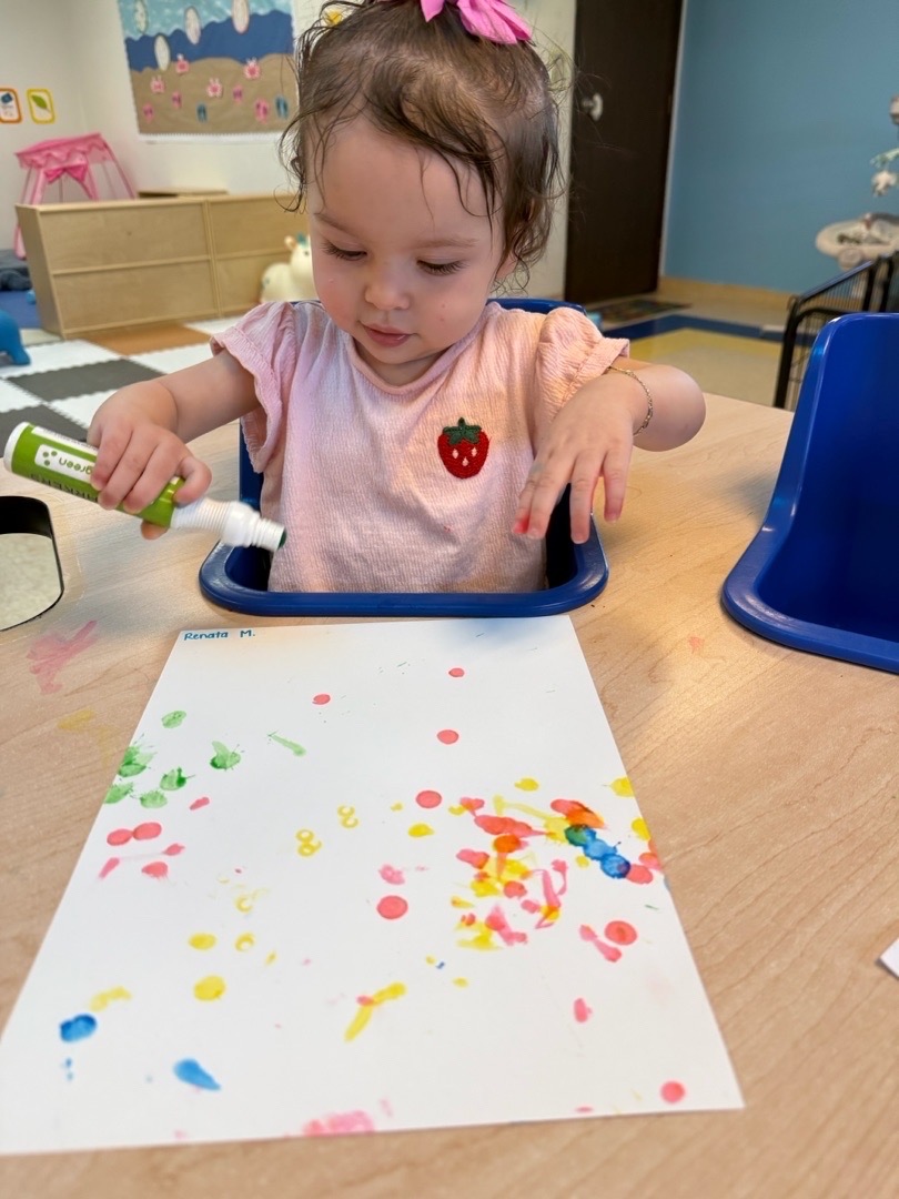 A child making colorful dots with a paint marker