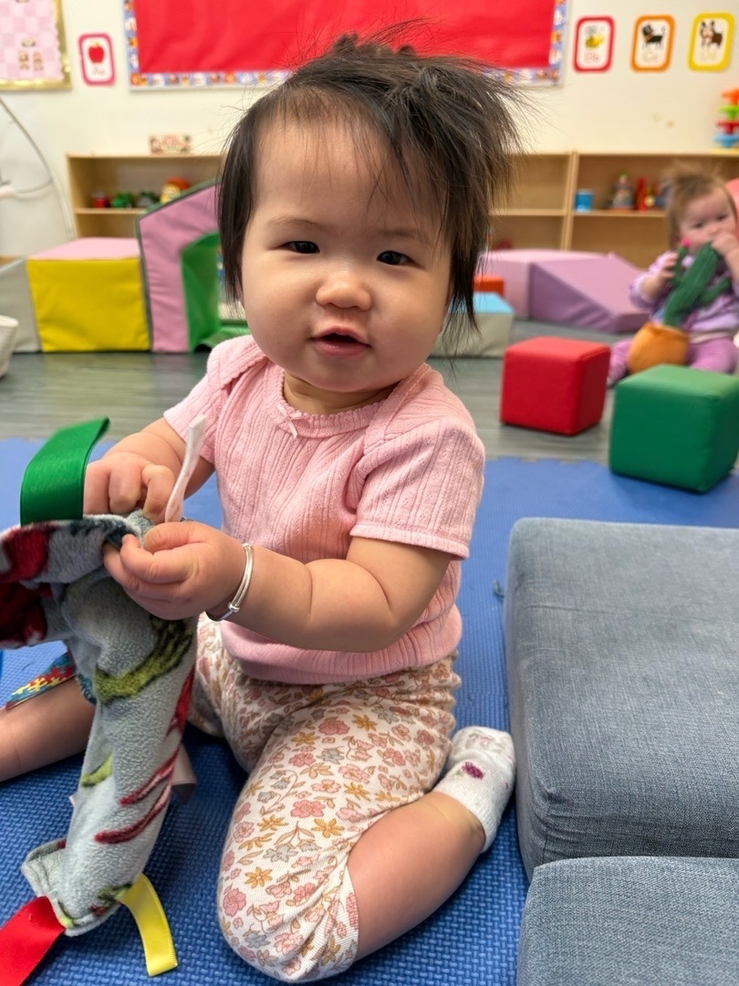 A child holding a toy while sitting beside the soft play area