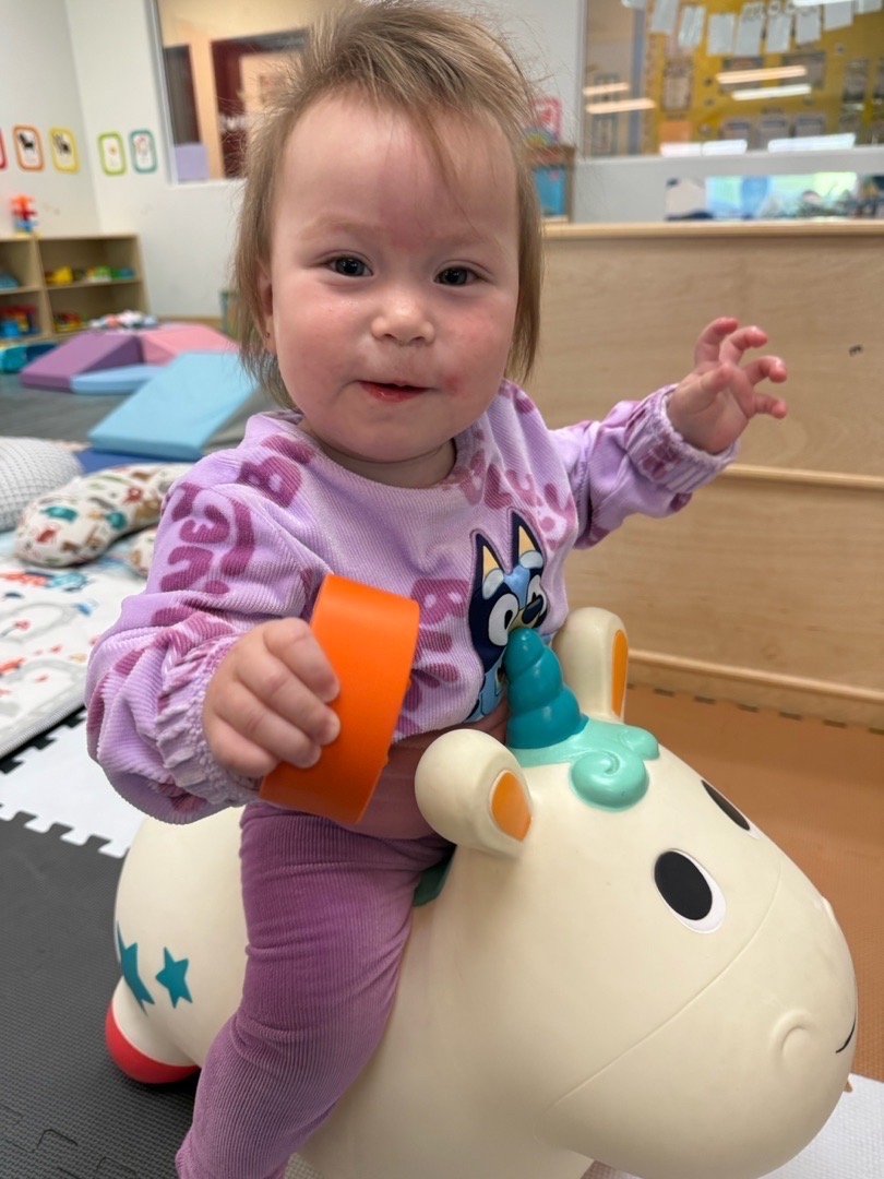 A child smiling on a white ride-on toy