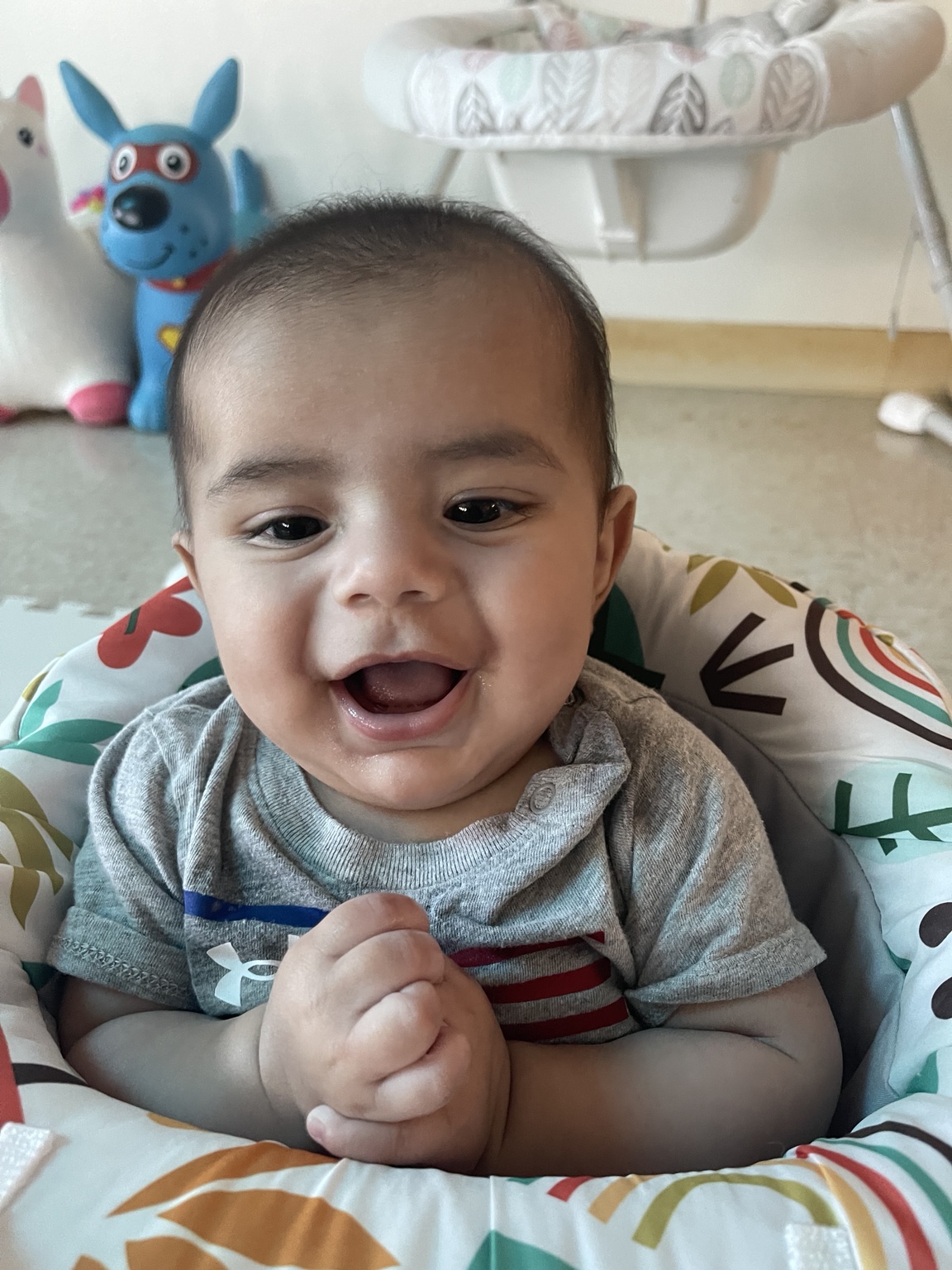 A smiling baby sitting in the infant classroom