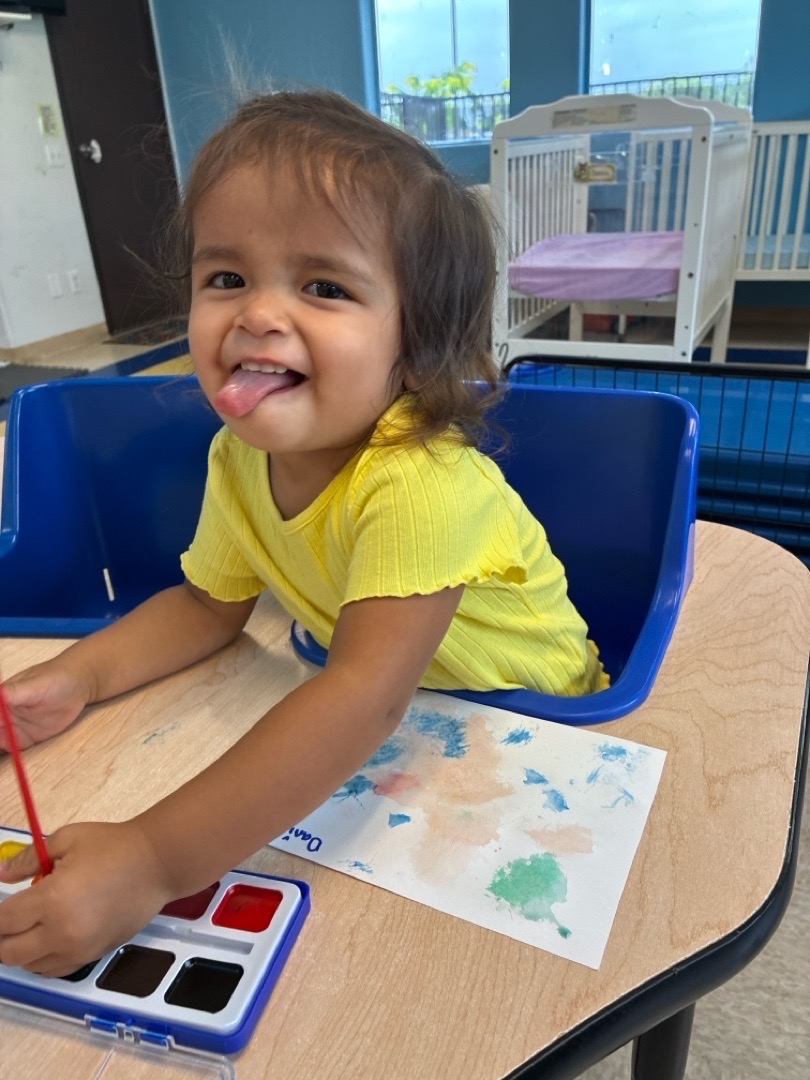 A child exploring watercolor paints at a classroom table