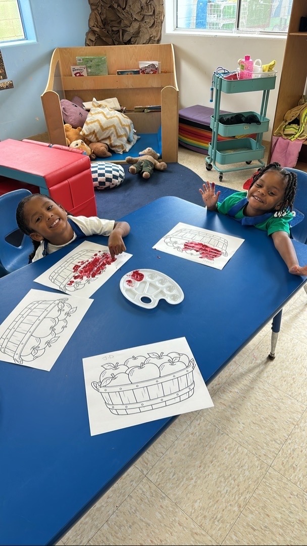 Two smiling children painting apple pictures together