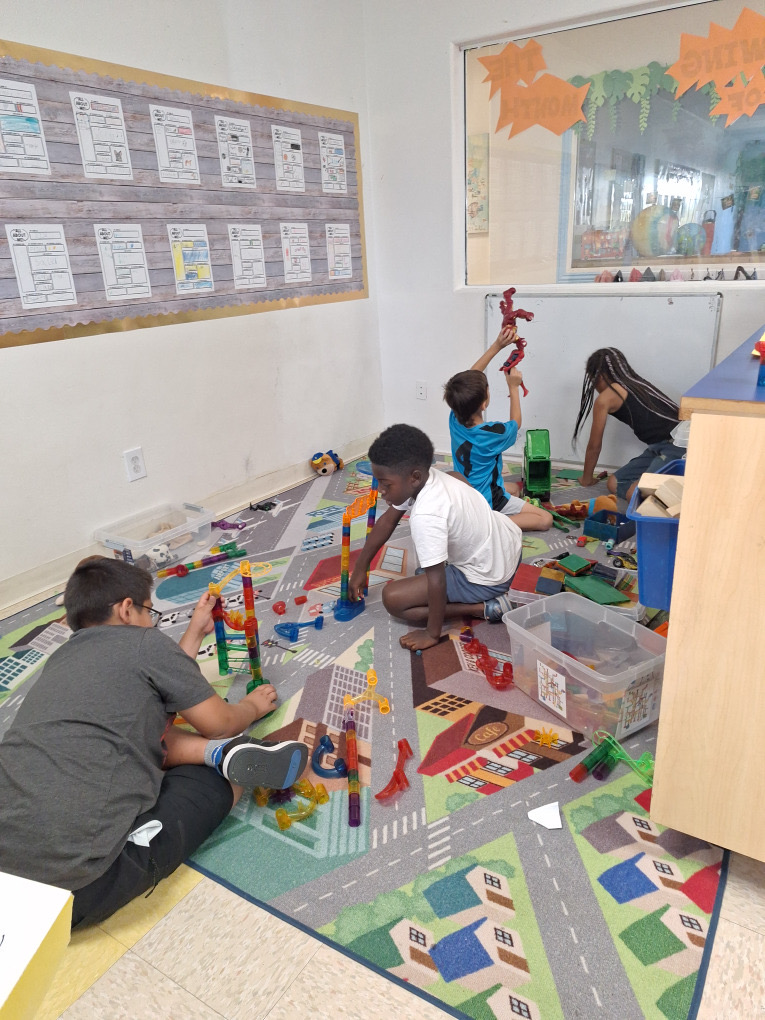 Children building marble runs and playing together on a road-pattern rug