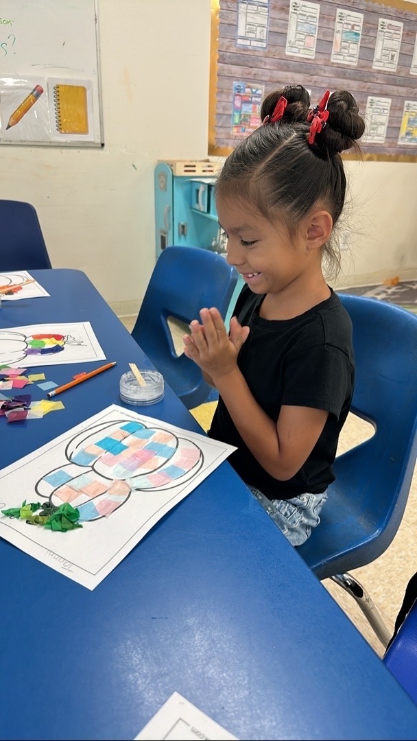 A child making a pumpkin collage with squares of colored paper