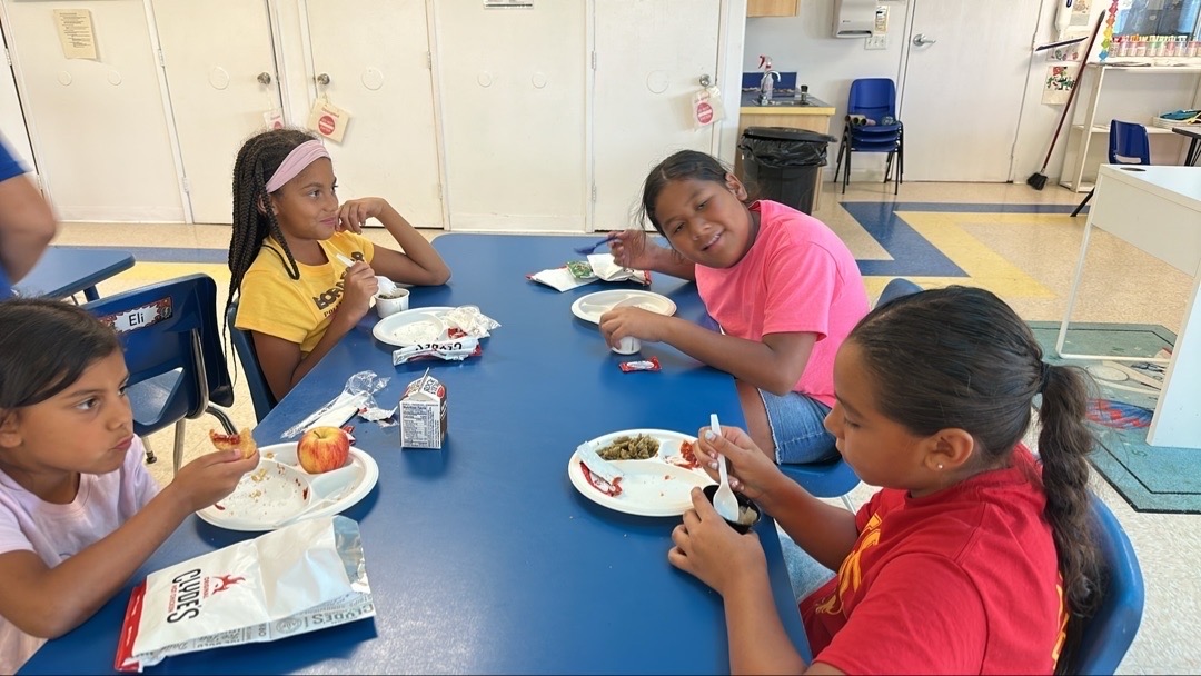 Children eating together around a blue classroom table