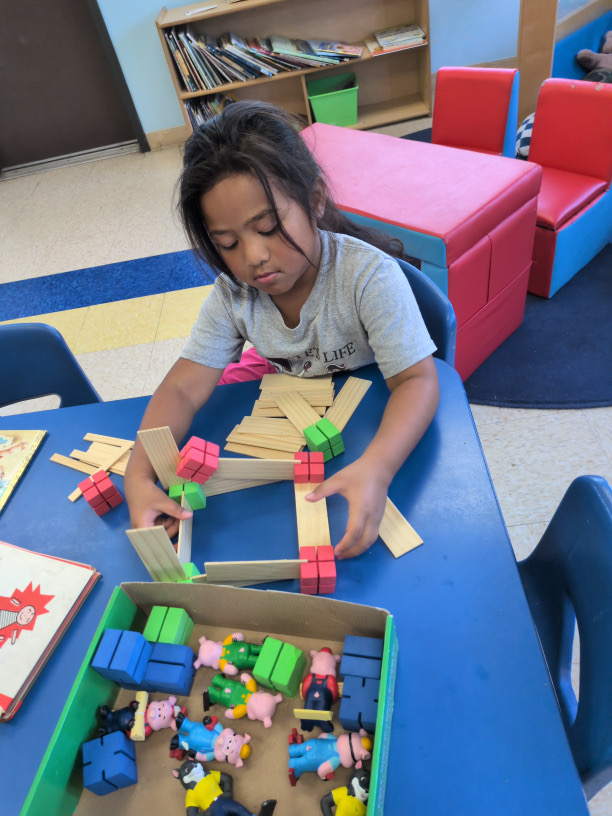 A child building a structure with wooden pieces and colorful blocks