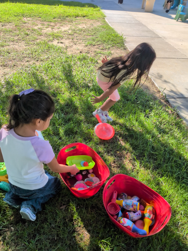 Children arranging baskets of pretend food on the grass